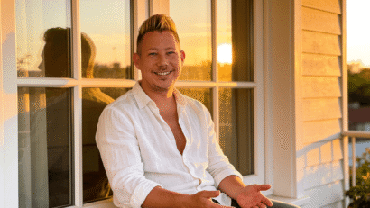 Man sitting in warm golden light with a relaxed and genuinely content expression, representing the idea that success and growth don't require suffering and that ease is a valid path forward